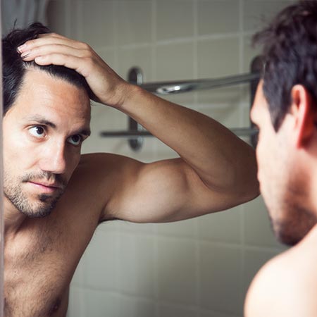 Man looking at receding hairline