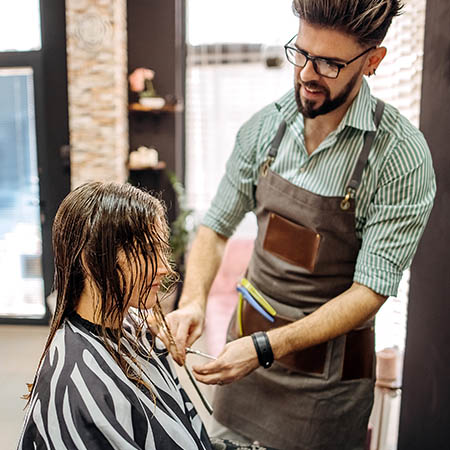 Male hairdresser cutting young ladies hair