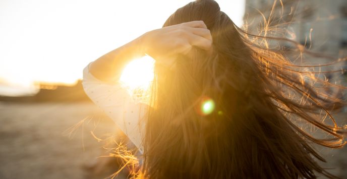 Woman’s hair glowing in bright sunlight showing healthy summer hair with natural shine