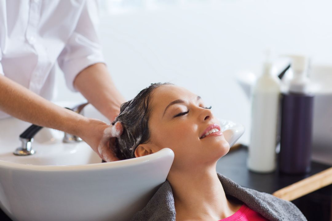 Relaxed salon client receiving a calming head massage.